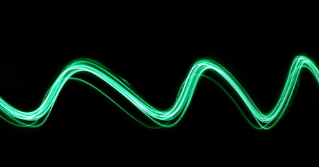 Wall Mural - Long exposure, light painting photography.  Vibrant abstract streaks of neon green color against a black background.