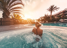 Young Influencer Woman Relaxing Inside Pool At Sunset Outdoor - Girl Enjoying Summer Vacation In A Tropical Destination - Travel, New Jobs Trends And Holiday Concept - Soft Focus On Her Body
