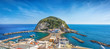 Panoramic view of beautiful coast of village Sant'Angelo, giant green rock in blue sea near Ischia Island, Italy.