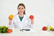 © LIGHTFIELD STUDIOS - front view of smiling dietitian in white coat holding cut orange and grapefruit