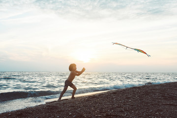 Little boy playing with kite on tropical beach. Summer vacation concept, child playing on sandy beach