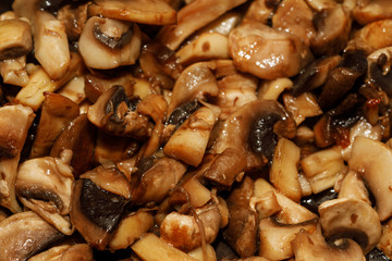 Fried champignon mushrooms in a pan closeup background texture