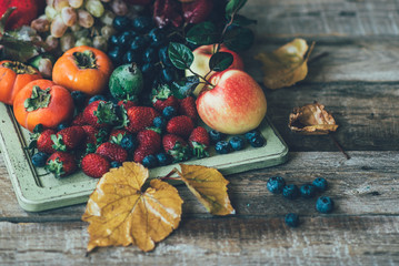 Wall Mural - Rainbow fruits background. Strawberries, blueberries apples, grapes, persimmon, pomegranate on dark wooden table. Selective focus. Toned image.