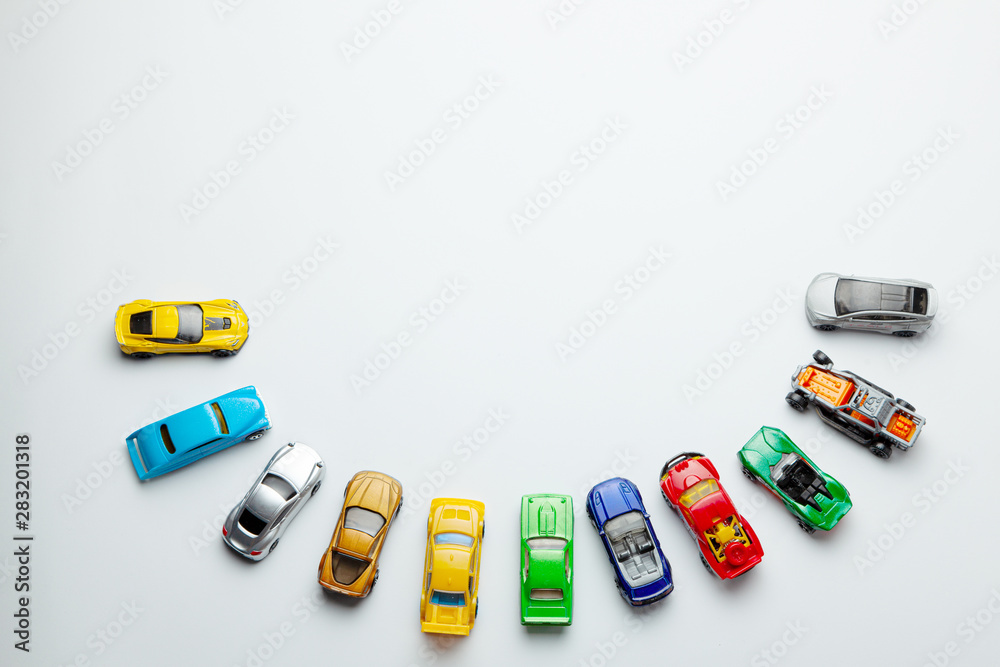 Many colored little toy cars on a gray background. - obrazy, fototapety, plakaty 