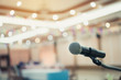 © smolaw11 - Microphone on abstract blurred conference hall prepare for speaker on stage in seminar room. lecture to audience university with bokeh background. Business meeting or education teaching image