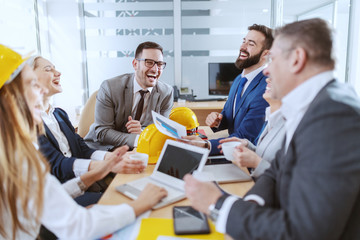 Group of cheerful dedicated Caucasian architects working on project together. Boardroom interior.