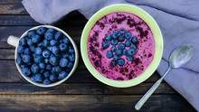  The Blueberry Bowl Is Full Of Vitamins For Your Breakfast. Fresh Berries And Berry Powder Are Sprinkled On The Surface. Cute Table Setting On A Dark Wooden Table
