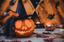 Close Up Carved Pumpkin In Witch Hat With Paper Silhouettes Of Bats, Castle, Ghosts On Wooden Background. Head Jack Lantern With Scary Evil Faces. Spooky Holiday Symbol, Concept. Copy Space.