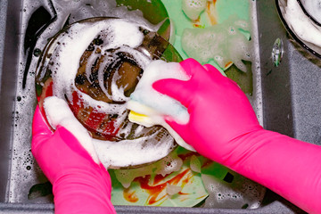 Wall Mural - The process of washing plates in the sink, hands and plates closeup. Detergent foams. Cleaning.