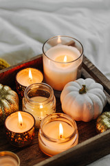burning candles pumpkin decoration on wooden tray with warm plaid in bed. autumn style. hygge concep