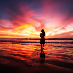 Wall Mural - woman walking alone on the beach in the sunset