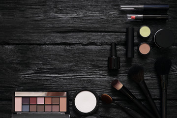 Makeup brushes and cosmetics flat lay background with a copy space. Make up accessories on a black wooden table.