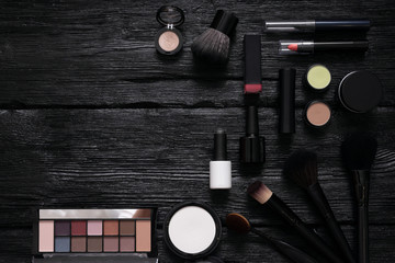 Makeup brushes and cosmetics flat lay background with a copy space. Make up accessories on a black wooden table.