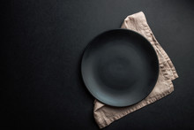 Elegant Black Table Setting: Plates, Napkin And Silverware Over Black Background. Flat Lay. Copy Space