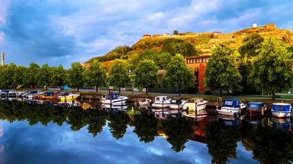 Wall Mural - Halden, Norway. View of the boats and yachts with Fredriksted fortress at the background. Time-lapse in the evening with cloudy sky in summer, zoom in