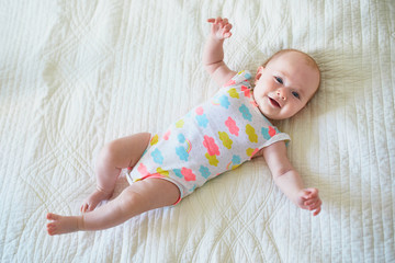 Wall Mural - Baby girl lying on bed and smiling