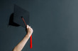 Raising hands with graduation cap on gray board.Celebration Education Graduation Student Success Learning Concept