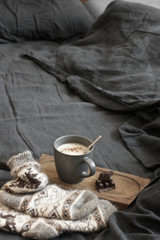 Poster - Coffee latte with chocolate and woolen socks in unmade bed