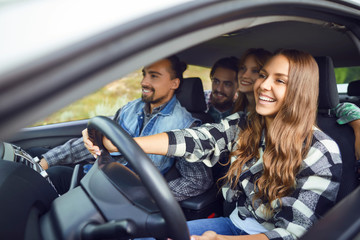 A group of happy friends are driving in a car.