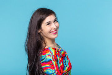 Wall Mural - Cheerful young brunette woman with long hair posing on a blue background with copy space. The concept of a beautiful and well-groomed woman