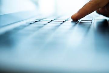 finger push the enter button of notebook keyboard. selective and soft focus. subject is blurred