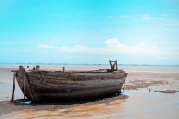 Naklejka na meble Old wooden boat on the beach in the middle of the sun by the sea