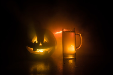 Glass of cold light beer with pumpkin on a wood background for Halloween. Glass of fresh beer and pumpkin on a dark toned foggy background