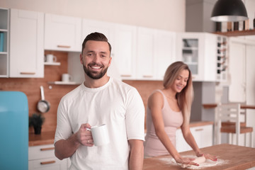 smiling man with a Cup of tea standing in the kitchen