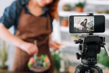 Florist video blog. Cropped shot of woman using smartphone camera to stream home gardening online tutorial.