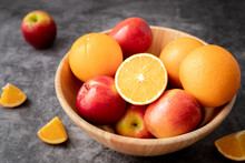 Wooden Plate With Orange And Apple Fruit On Kitchen Table.