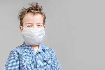 Boy child in medical mask on gray background in studio.