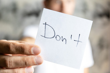 man holds in his outstretched hand a sheet with the inscription 