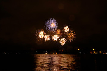 Beautiful colorful fireworks in sky over river. Big festive evening event with great pyrotechnic show.  