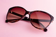 Classic oval oversized brown tortoise sunglasses closeup on pink background