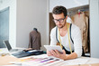 © pressmaster - Young confident fashion designer with tablet scrolling through online ideas