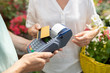 © pressmaster - Contemporary female buyer using credit card to pay for some fresh potted flowers