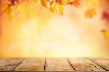 Wall Mural - wooden table and blurred autumn background. autumn concept with red-yellow leaves background.