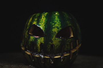 green watermelon burns with fiery flame on the scary holiday of october halloween