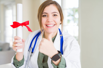 Sticker - Beautiful young doctor woman holding degree happy with big smile doing ok sign, thumb up with fingers, excellent sign