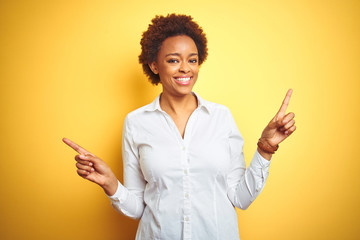 African american business woman over isolated yellow background smiling confident pointing with fingers to different directions. Copy space for advertisement