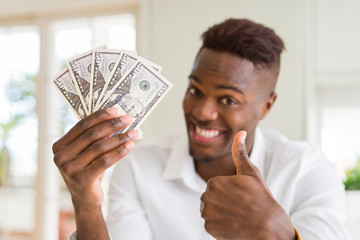 Canvas Print - African american man holding fifty dollars bank notes happy with big smile doing ok sign, thumb up with fingers, excellent sign