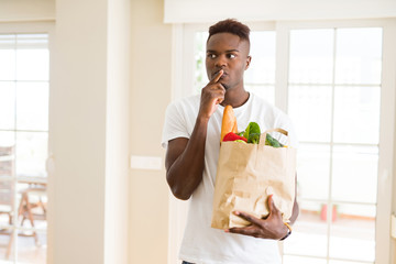 Canvas Print - African american man holding paper bag full of fresh groceries serious face thinking about question, very confused idea