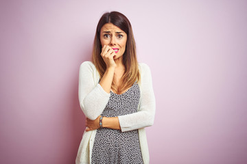 Canvas Print - Young beautiful woman standing over pink isolated background looking stressed and nervous with hands on mouth biting nails. Anxiety problem.