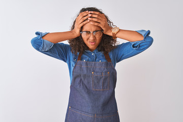 Wall Mural - Young brazilian chef woman wearing apron and glasses over isolated white background suffering from headache desperate and stressed because pain and migraine. Hands on head.