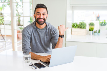 Sticker - Handsome hispanic man working using computer laptop pointing and showing with thumb up to the side with happy face smiling