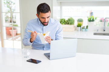 Wall Mural - Business man eating asian food from delivery while working using computer laptop at the office