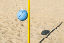 A Blue Ball And Yellow Pole On The Beach For Playing Tetherball.