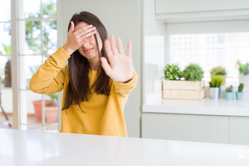 Sticker - Beautiful young woman wearing yellow sweater covering eyes with hands and doing stop gesture with sad and fear expression. Embarrassed and negative concept.