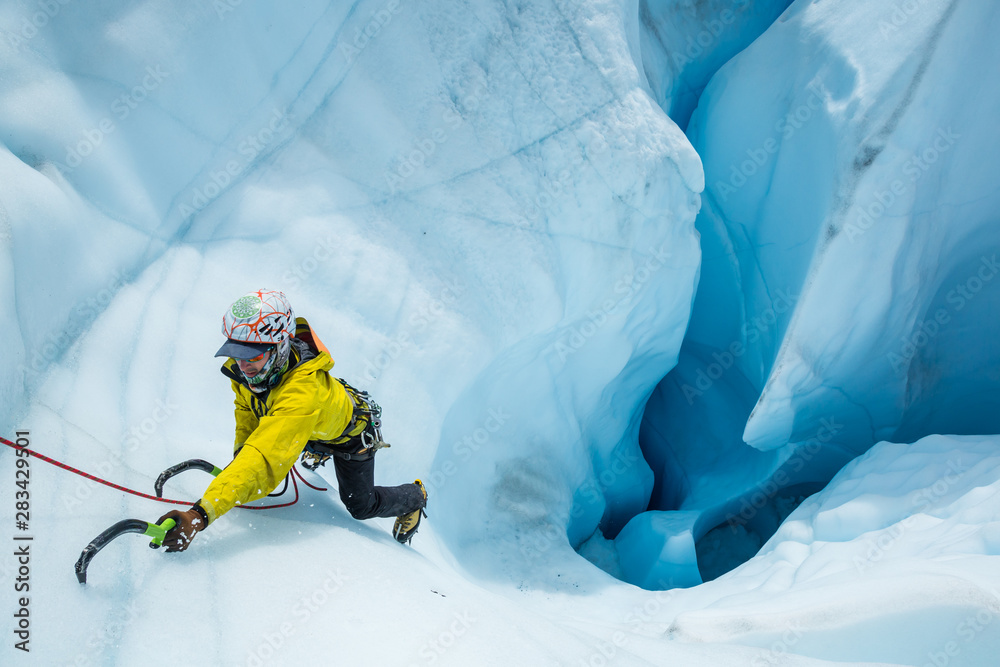 Ice climber expertly ascending out of a massive mouin in the Matanuska Glacier - obrazy, fototapety, plakaty 
