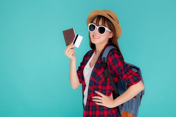 Beautiful young asian woman wear hat and sunglasses with showing credit card and passport to travel summer trip isolated on blue background, girl journey in vacation with payment finance on card.